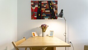 A wooden dining table with two chairs, a vase with flowers, and two framed pictures. - Colourful Apartment Under the Cropolis (Athens)