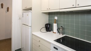 A kitchen with white cabinets, a white countertop, a black stove, and a green tiled backsplash. - Colourful Apartment Under the Cropolis (Athens)