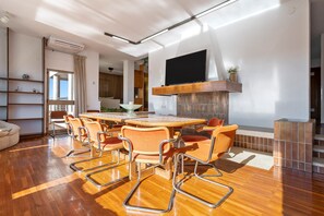 A modern living room with a wooden dining table, orange chairs, a fireplace, and a TV mounted on the wall. - Villa 'De L'ebre' with Private Pool, Wi-Fi and Air Conditioning (Deltebre)