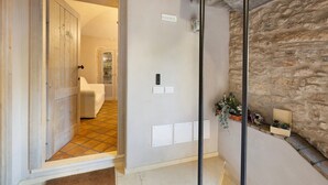 A room with a wooden door, a stone wall, and a small plant on the floor. - Apartment "Casa Virginia - Corbezzolo" with Shared Pool & Wi-Fi (Orco Feglino)