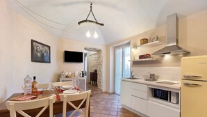 A kitchen with white cabinets, a built-in microwave, a stove, and a hanging light fixture. - Apartment "Casa Virginia - Corbezzolo" with Shared Pool & Wi-Fi (Orco Feglino)