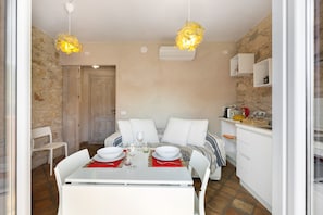 Un espacio habitable pequeño con comedor, kitchenette y una pared de piedra.