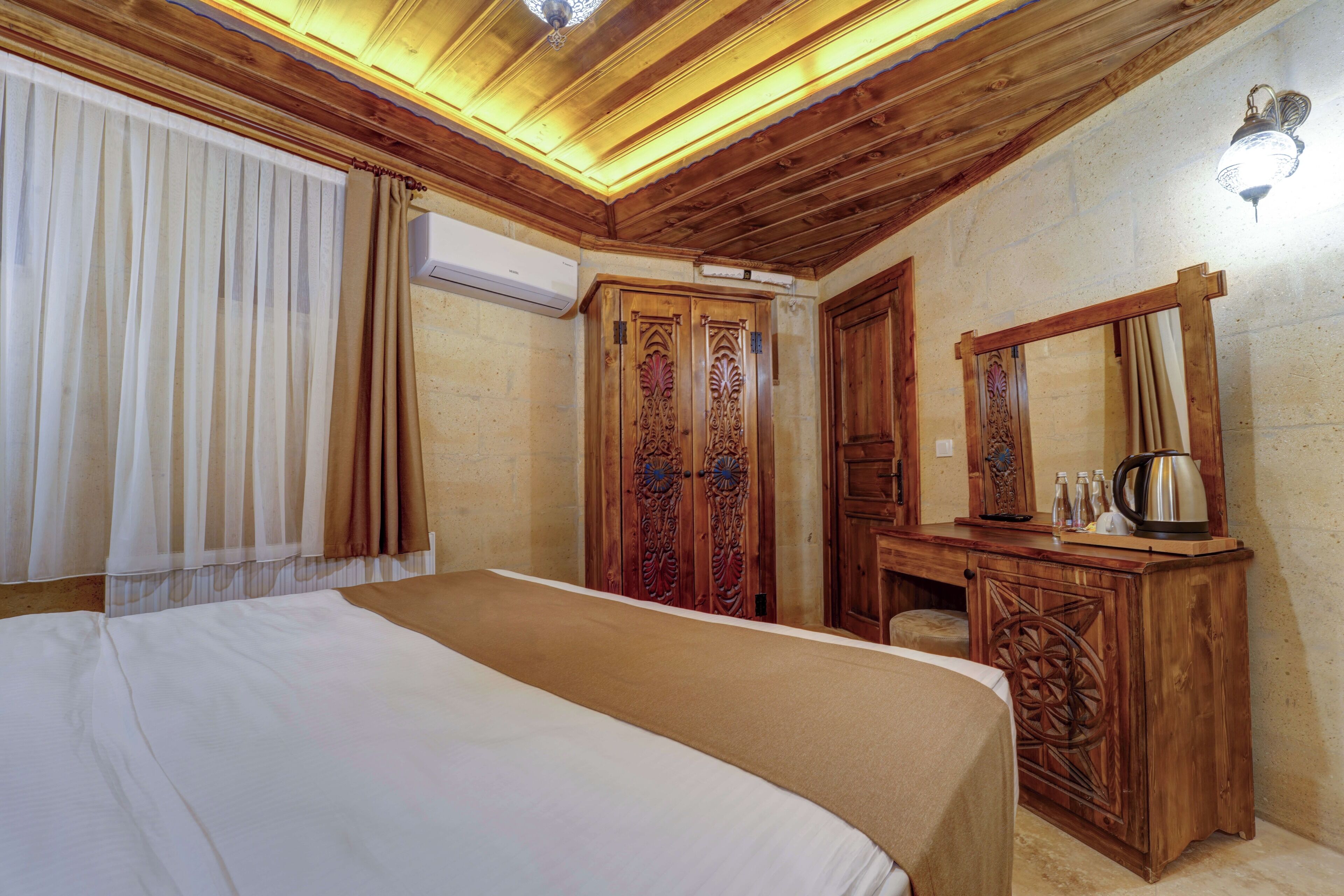 A bedroom with a large bed, wooden wardrobe, and a mirror.