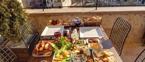 A table with a variety of dishes and a scenic view of mountains and hot air balloons.