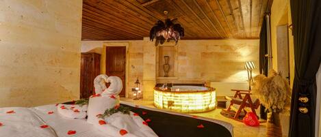A room with a bed, a bathtub, and a wooden ceiling.