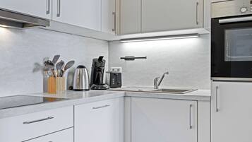 Een moderne keuken met witte kastjes, roestvrijstalen apparatuur en een inbouwoven.