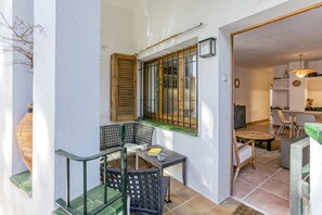 Un balcone con mobili in vimini, una finestra con persiane in legno e vista su una sala da pranzo.