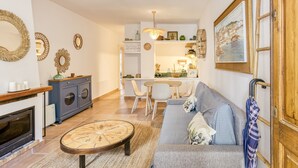 Una sala de estar con un sofá, una mesa de centro, una chimenea y un comedor con sillas y una mesa.