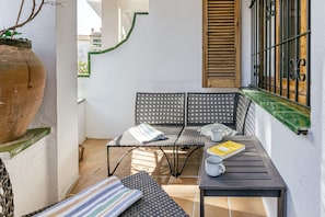 Ein kleiner Außenbereich mit Tisch und Stühlen, einem Blumentopf und einem Fenster mit Gitterstäben.