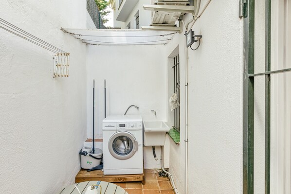 A compact laundry room with a washing machine, sink, and a small table. - Apartment 'Calella Pallafrugell' with Private Terrace (Palafrugell)