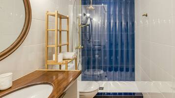 A bathroom with a wooden vanity, a toilet, a shower with a blue curtain, and a mirror.
