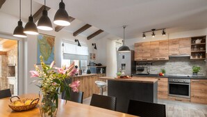 A modern kitchen with wooden cabinets, a central island, and pendant lighting. - Villa Kalista Istriana (Pula)