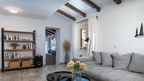 A living room with a grey sofa, a bookshelf, a coffee table with a vase of flowers, and a lamp. - Villa Kalista Istriana (Pula)
