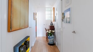 A hallway with a wooden floor, white walls, and a door at the end. - Culture and Colour, by Veeve (Paris)