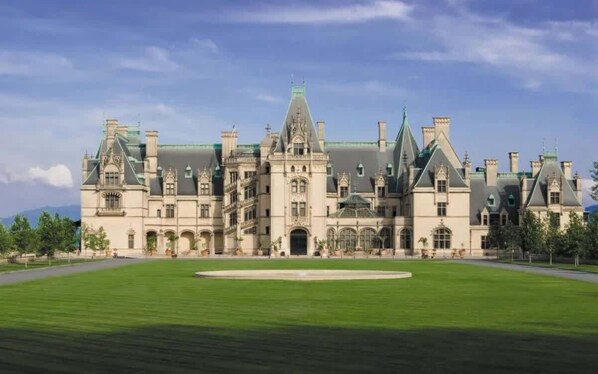 A large, historic building with a symmetrical facade, multiple chimneys, and a central entrance.