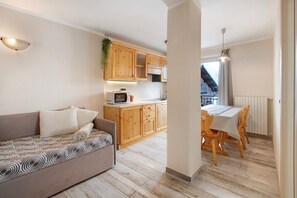 Una cocina moderna con armarios de madera, un rincón comedor con mesa y sillas, y un sofá con cojines estampados.