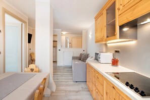 A compact kitchen with wooden cabinets, a microwave, a toaster, and a stove.