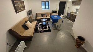 Un espacio habitable compacto con sofá, una mesa de comedor y una kitchenette.