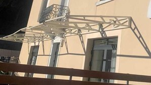 Un edificio de varios pisos con fachada color crema, numerosas ventanas y un balcón con barandilla metálica.