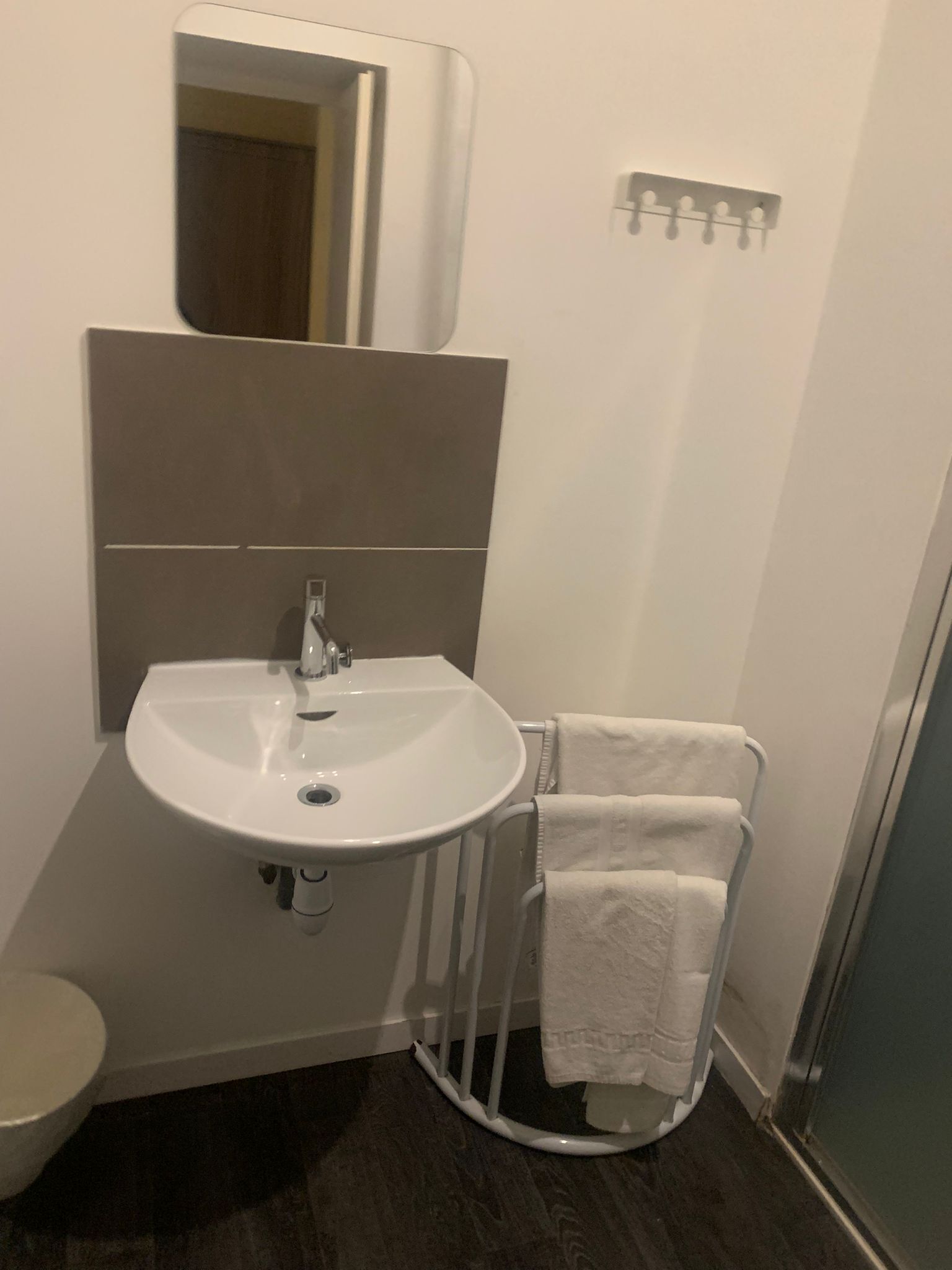 A bathroom with a white sink, a mirror, and a towel rack.