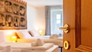 Ein Hotelzimmer mit Holztür, einem Bett, einem Nachttisch und einem an der Wand hängenden Kunstwerk.