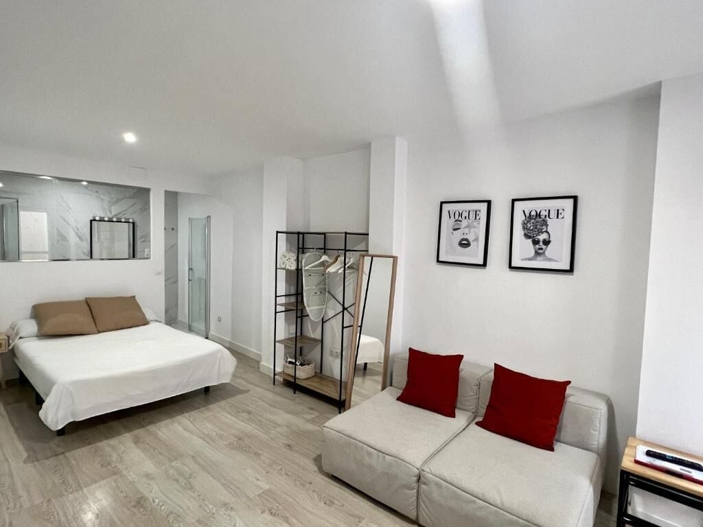 A modern bedroom with a bed, a sofa, a wardrobe, and two framed pictures on the wall.