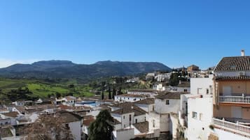 A town with white buildings and red-tiled roofs, surrounded by green hills and mountains.