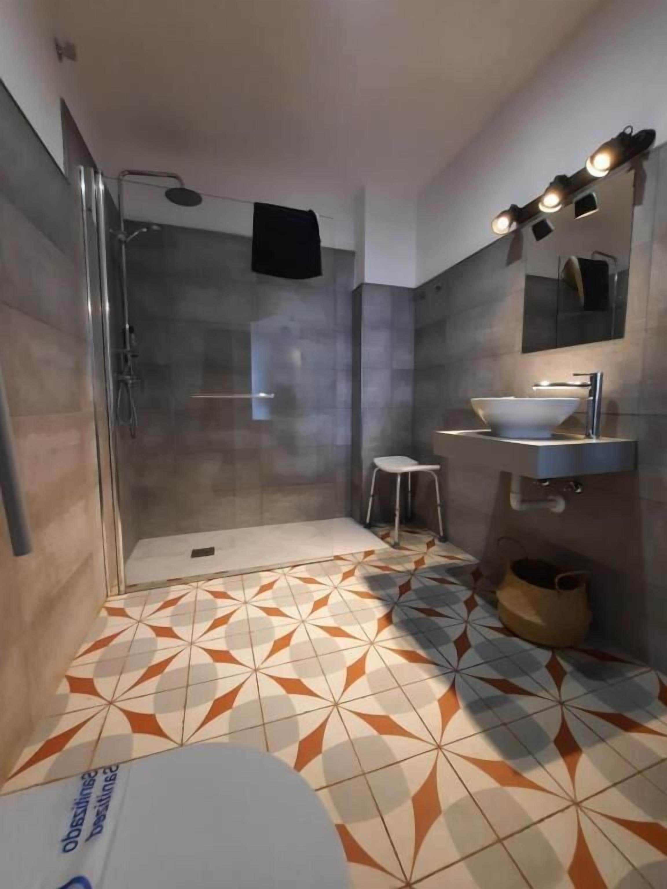 A modern bathroom with a glass-enclosed shower, a white sink, and a vanity with a mirror.