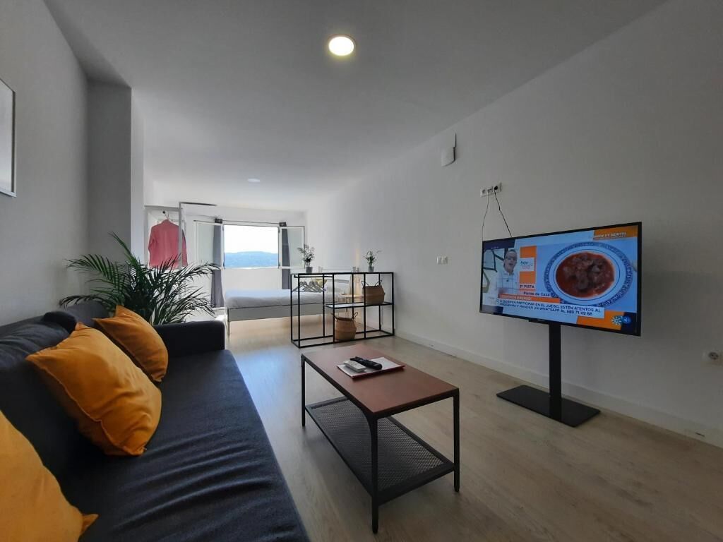 A modern living room with a sofa, coffee table, and a flat-screen TV.