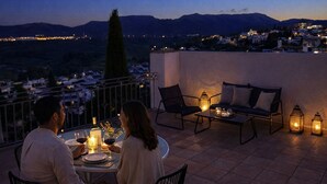A terrace with a dining table, chairs, and lanterns. - Apartamentos Avanel (Ronda)