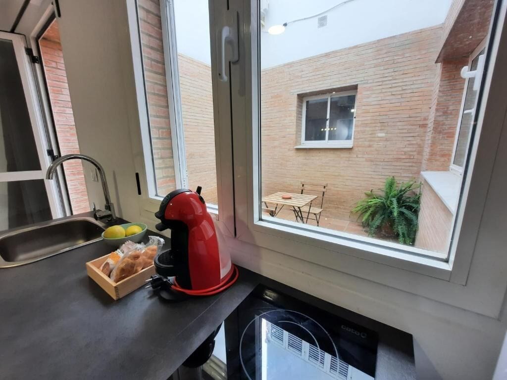 A kitchen with a window overlooking a brick wall and a small patio area.