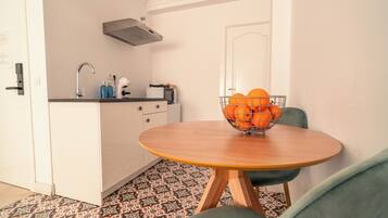 Una cocina compacta con un fregadero, microondas y un tazón de naranjas sobre una mesita.