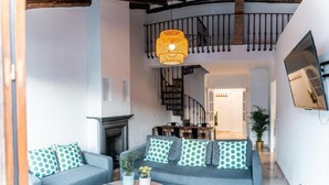 A modern living room with a grey sofa, a round coffee table, and a fireplace. - Apartamentos Avanel (Ronda)