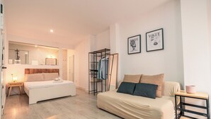 A modern bedroom with a bed, a sofa, a wardrobe, and a bedside table. There are two framed pictures on the wall. - Apartamentos Avanel (Ronda)