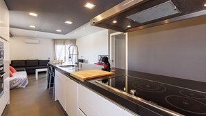 Eine moderne Küche mit einem schwarzen Kochfeld, weißen Schränken und einer Holz-Schneidebrett.