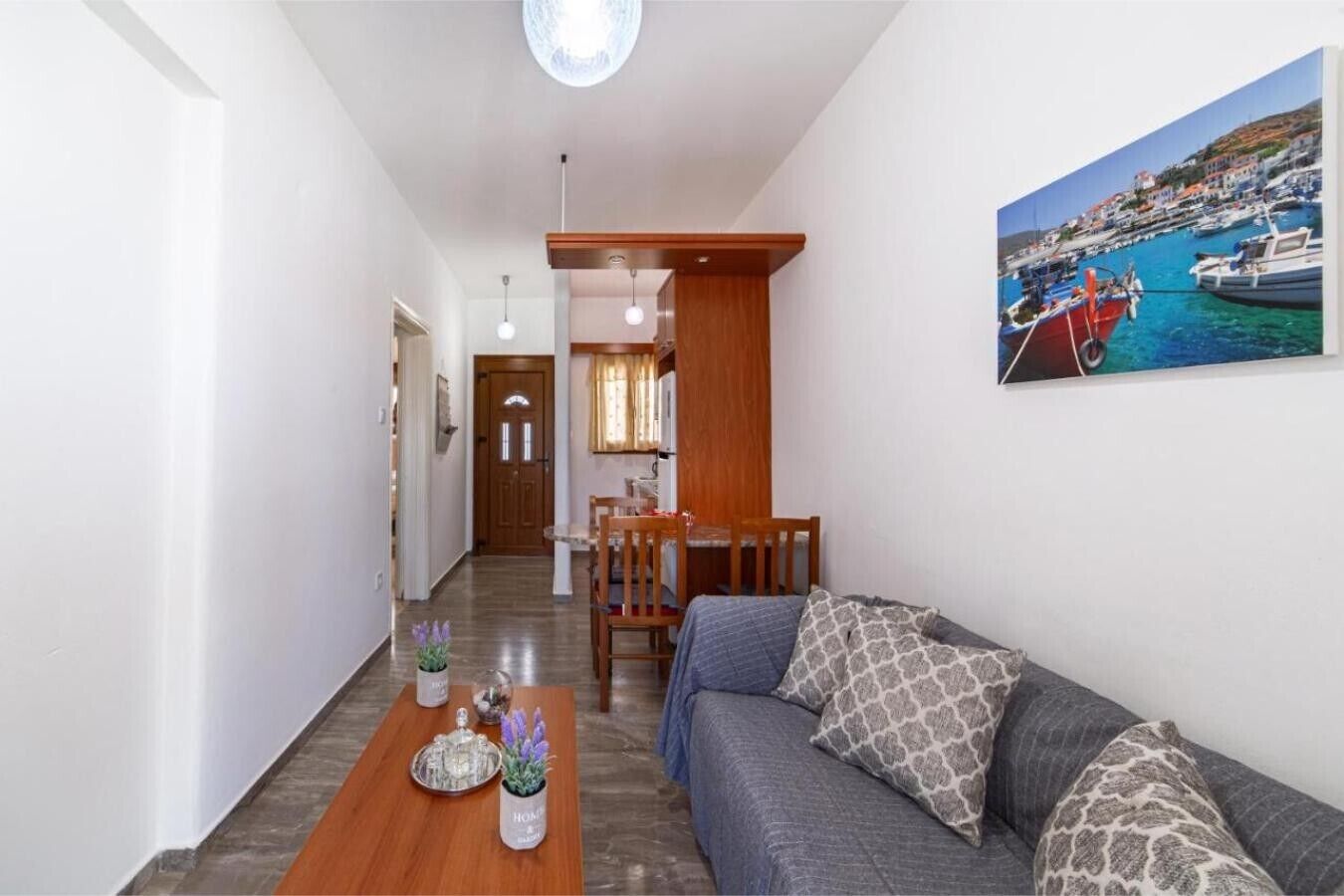 A living room with a sofa, a coffee table, and a painting of a harbor.