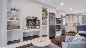 Eine moderne Küche mit integrierten Geräten, einem Kamin und einem Essbereich mit Tisch und Stühlen.