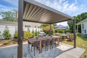 An outdoor patio with a covered dining area, a grill, and outdoor furniture. - Tee n’ Sea | Luxury Getaway - Golf & Coastal Views (Groton)