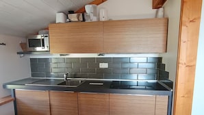 A kitchen with a stainless steel sink, wooden cabinets, and a microwave.