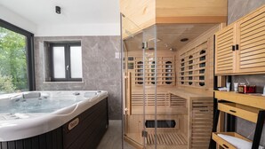 A modern bathroom with a hot tub, wooden sauna, and a glass-enclosed shower area. - Amazing home in Nedescina with sauna (Nedescina)
