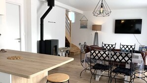 Una cucina moderna con isola in legno, piano cottura integrato e zona pranzo con tavolo alto e sedie.