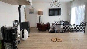Un soggiorno moderno con un tavolino in legno, una TV a parete e un'area pranzo con tavolo e sedie.