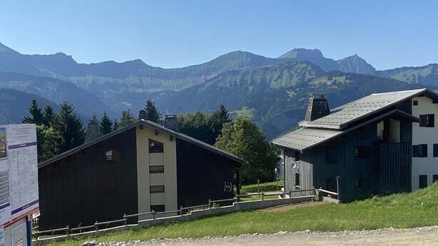 Eine Berglodge im schlichten, rustikalen Stil, mit einem großen Holzbau und einem kleineren Gebäude mit Satteldach.