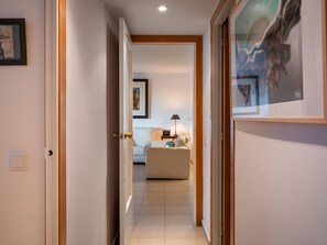 A hallway with a door leading to a room with a bed and a lamp. - Seaside Apartment with Pool and Private Parking (Torredembarra)