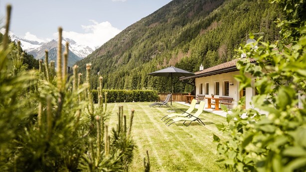 Une maison avec un patio, une pelouse et une vue sur les montagnes.