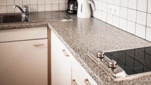 Une cuisine équipée d’un plan de travail en granit, d’une cuisinière, d’une machine à café et d’un évier.