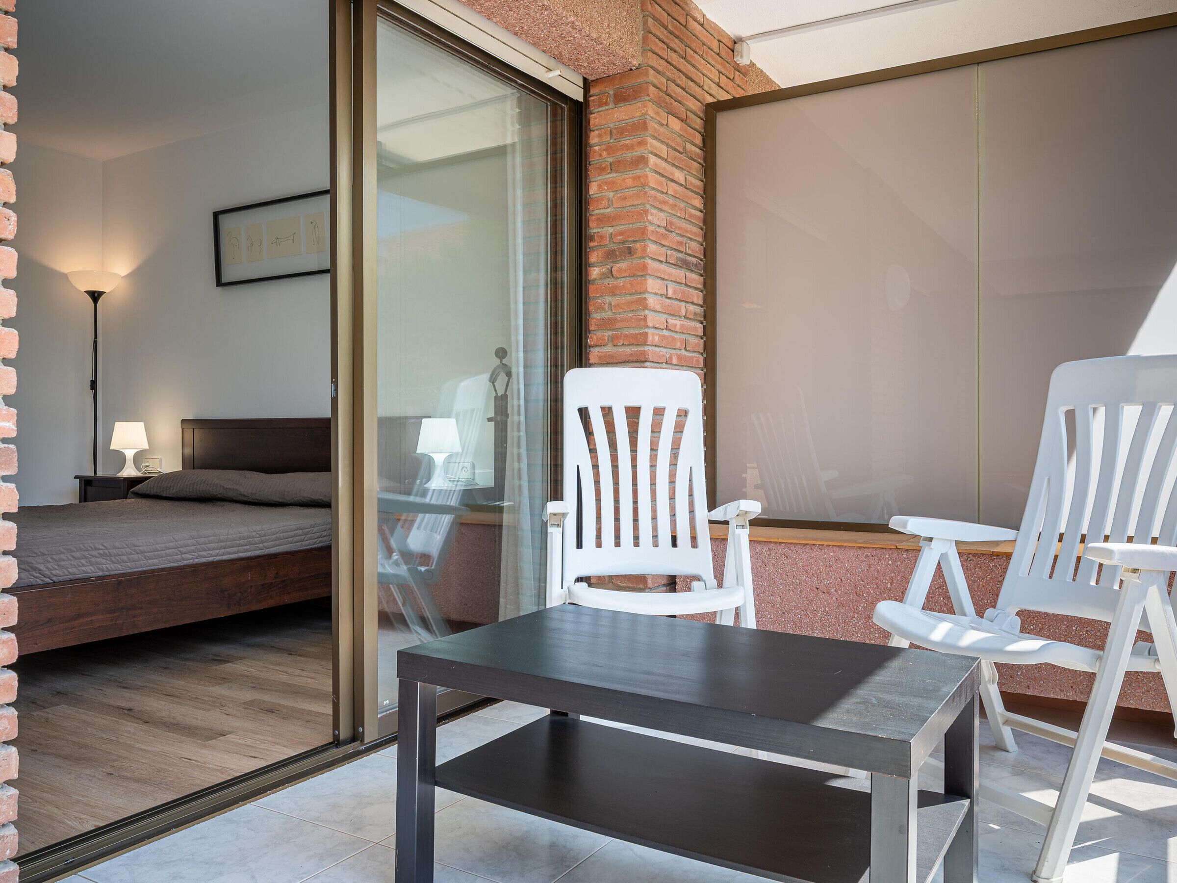 A hotel room with a bed, a table, and two white chairs.