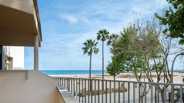 Ein Balkon mit Blick auf den Strand, Palmen und einen klaren Himmel.