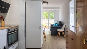 Eine moderne Küche mit Einbauofen, einem weißen Kühlschrank und einer Holz Arbeitsplatte.