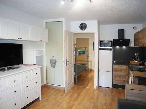 A compact kitchen with white cabinets, a built-in microwave, and a black range hood.
